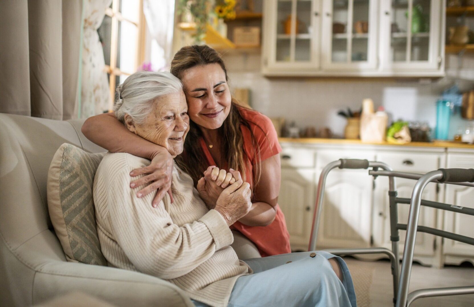 Caregiver hugging elderly woman beside walker